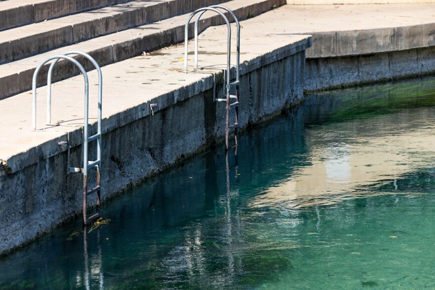 A rusty ladder sticks out of the San Marcos River at Sewell Park. Lines on the wall show the decreasing depth of the river due to the recent drought.