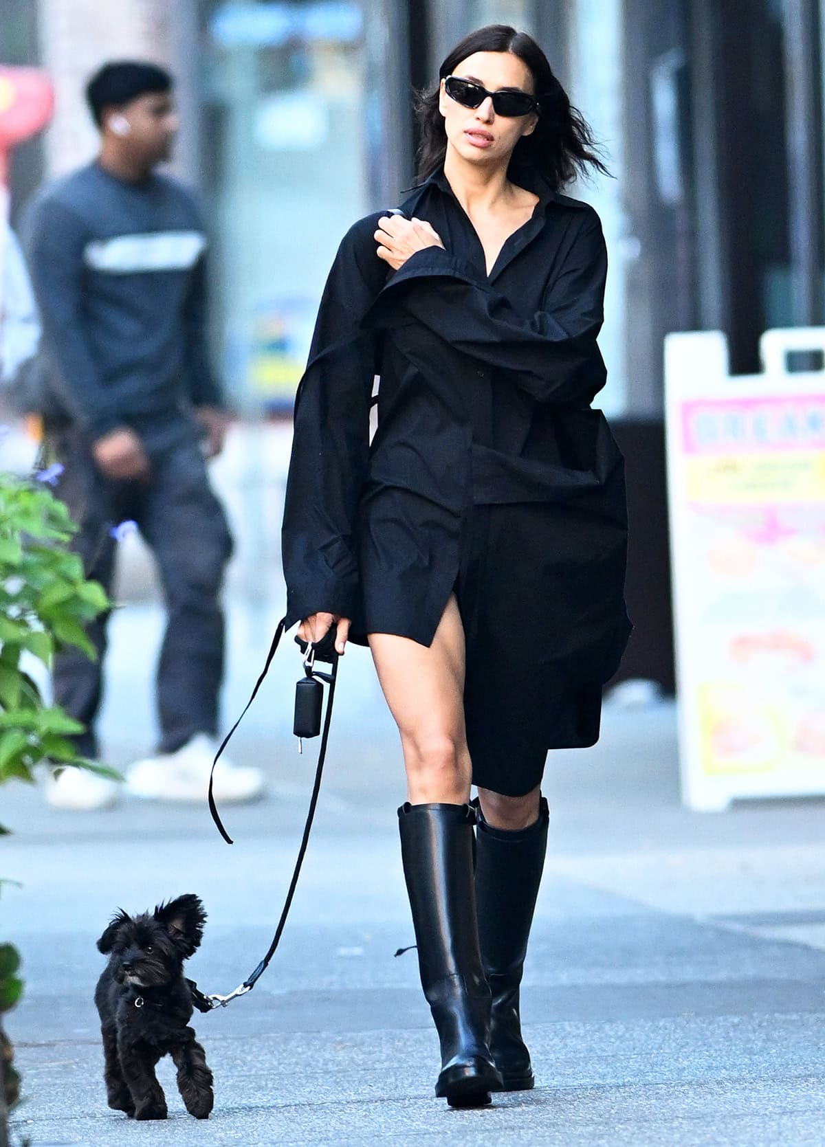 Irina Shayk parades her legs in an oversized black boyfriend shirt with an asymmetrical hem while walking her dog Peanut