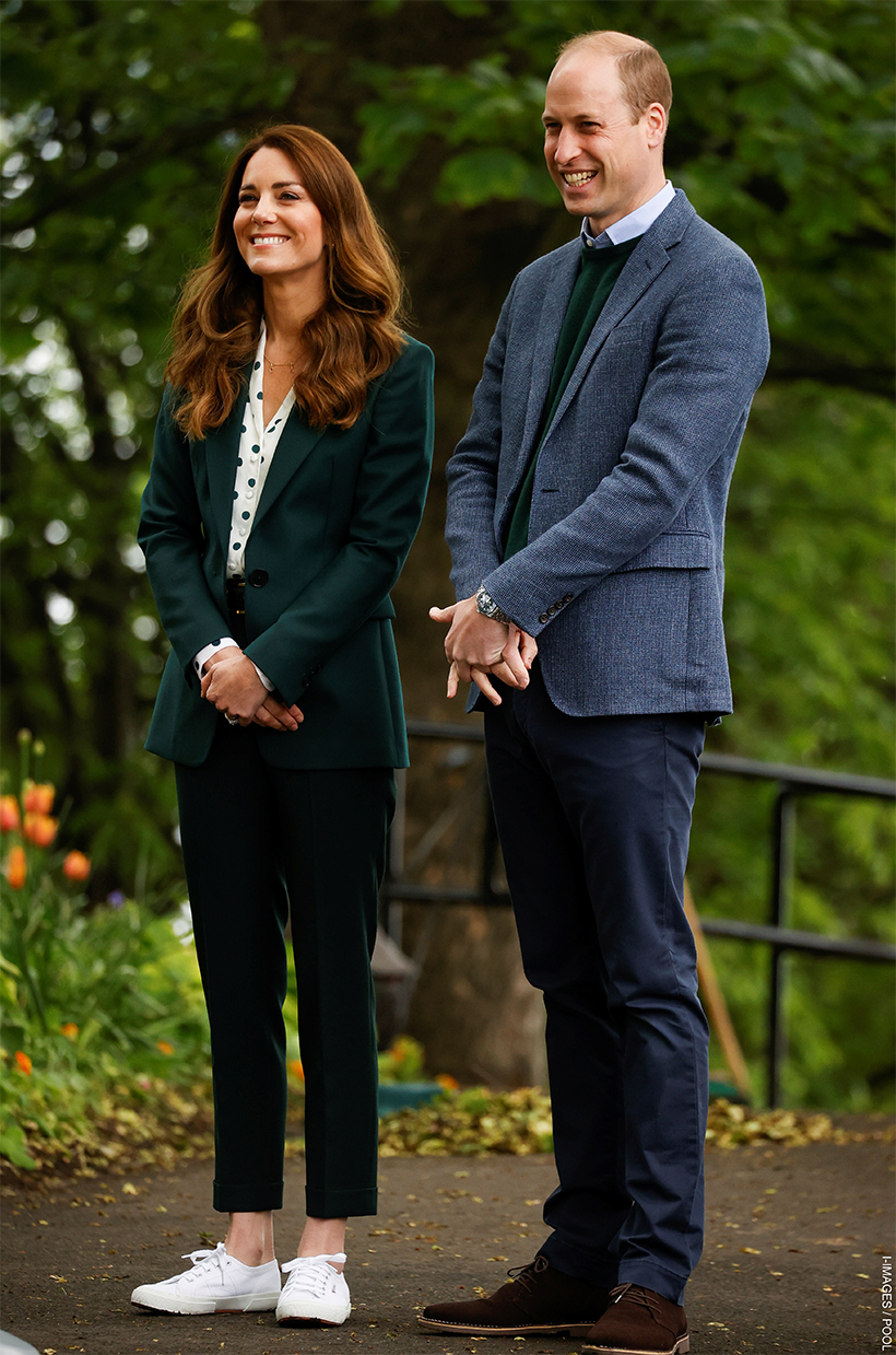 Kate Middleton wearing green trousers, blouse and a blazer, paired with white sneakers