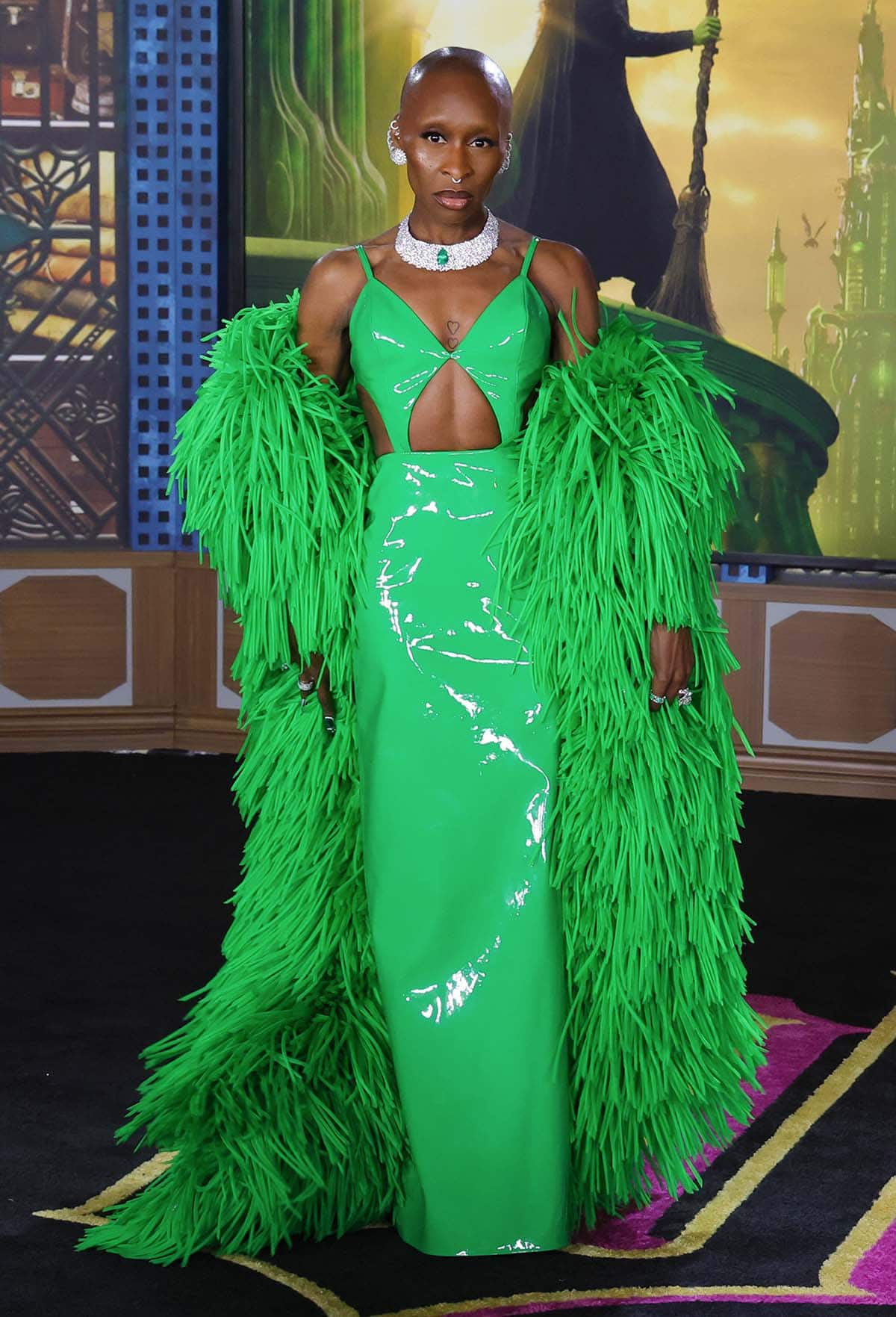 Cynthia Erivo styles her shiny green cutout dress with a fluffy green coat draped over her arms