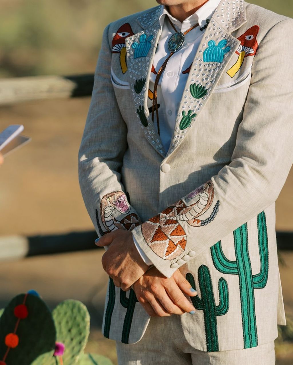 man wearing the custom embroidered suits trend for his outdoor ceremony with a western jacket featuring unique cactus and rattlesnake designs from Addicted Bespoken