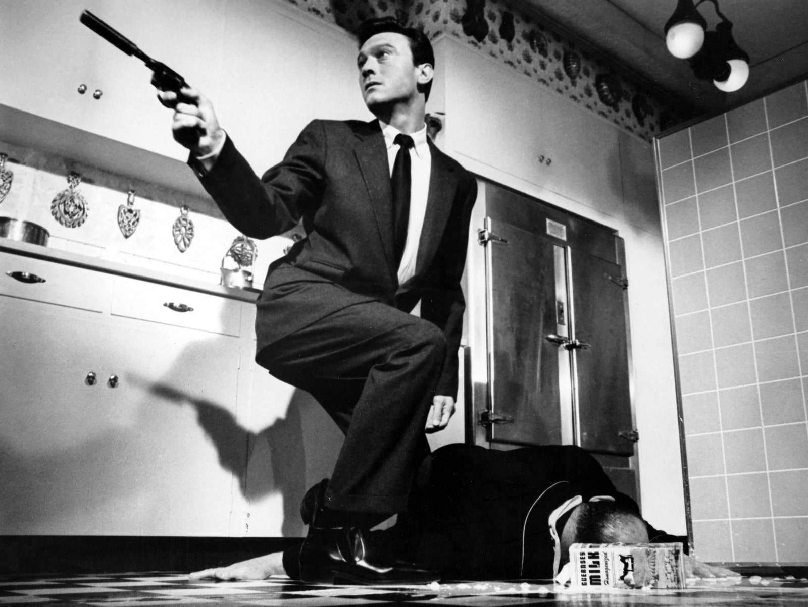 Image may contain Laurence Harvey Firearm Weapon Adult Person Gun Handgun Accessories Formal Wear and Tie