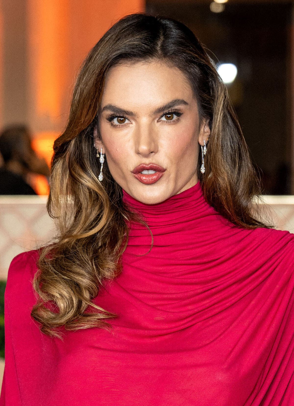 Alessandra Ambrosio wears her signature cat-eye makeup with rosy blush and lipstick, enhancing the look's sultriness