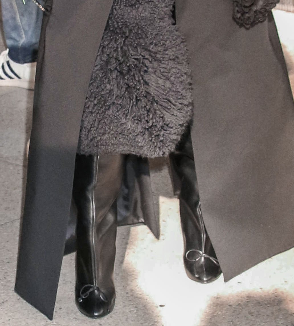 Cynthia Erivo teams her black coat and dress with black leather thigh-high boots with a cute, feminine bow at the toes