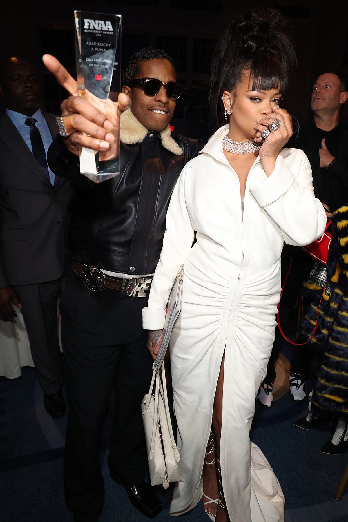 Rihanna looks regal in a white Alaia dress with a popped high collar, long sleeves, and floor-sweeping train as she accompanies A$AP Rocky at the 2024 FNAA