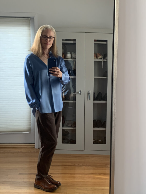 Woman in her 60s wearing a blue silk tunic and brown Eileen Fisher Carrot pants