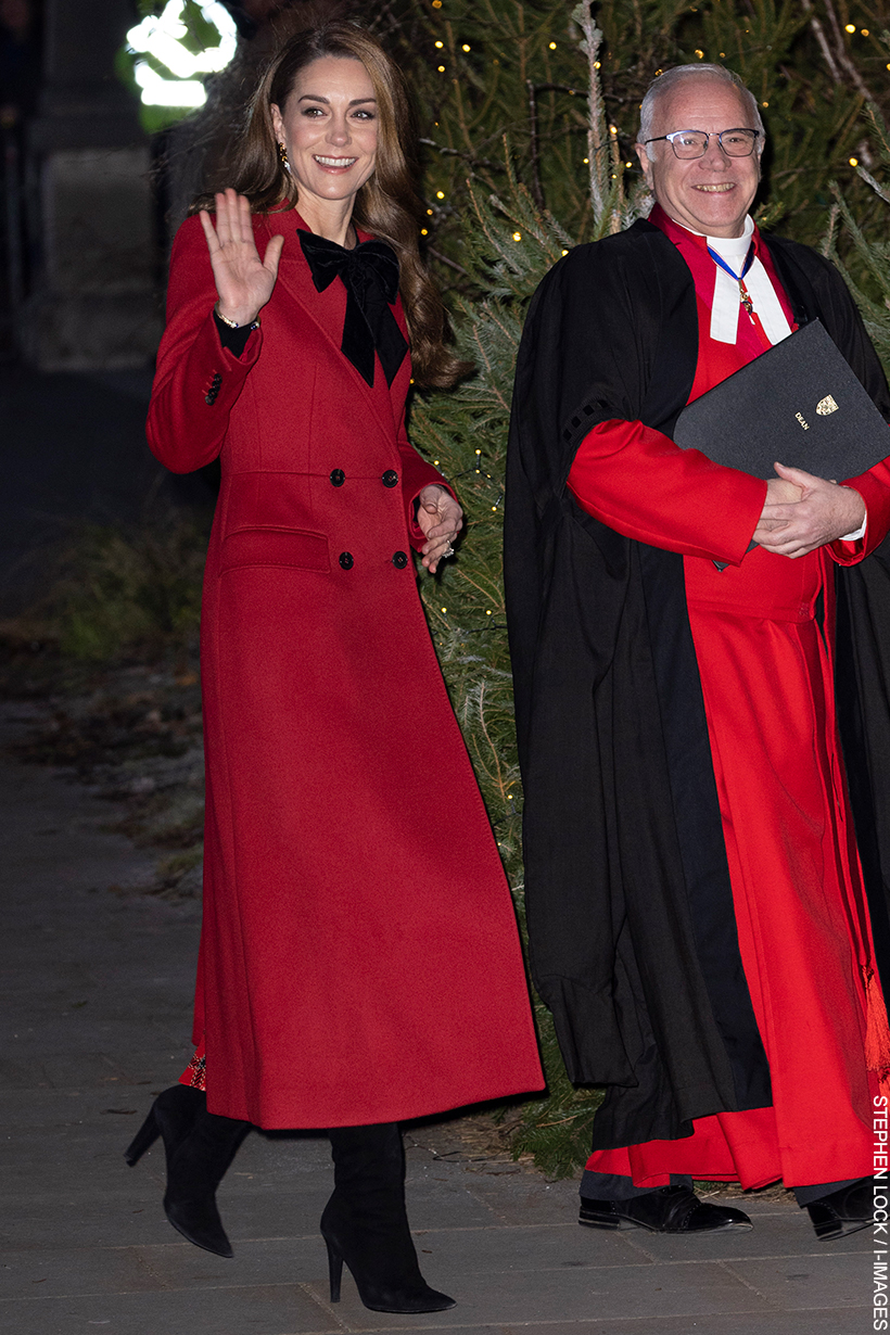 Kate Middleton wears a long red coat with a black velvet bow as she waves and walks into the 'Together At Christmas' Carol Service being held at Westminster Abbey.